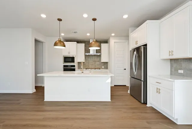 a large kitchen with stainless steel appliances kitchen island a large counter top and a stove top oven