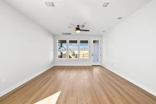 an empty room with wooden floor and a ceiling fan