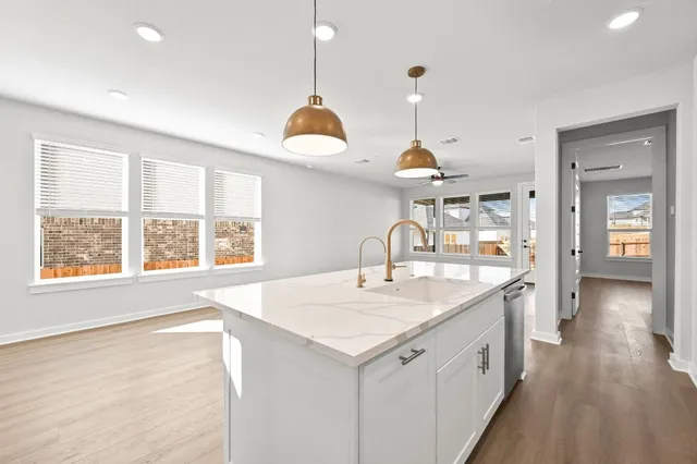 a kitchen with a sink a center island a wooden floor and a large window