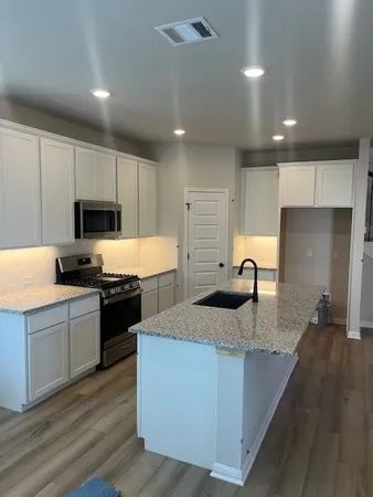 a large kitchen with granite countertop a large counter top stainless steel appliances and cabinets