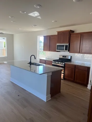 a kitchen with stainless steel appliances granite countertop a sink a stove and a wooden floors