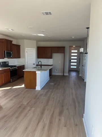 a view of kitchen with kitchen island wooden floor and stainless steel appliances