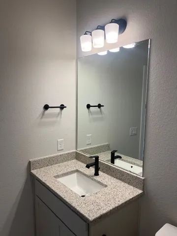 a bathroom with a granite countertop sink and a mirror