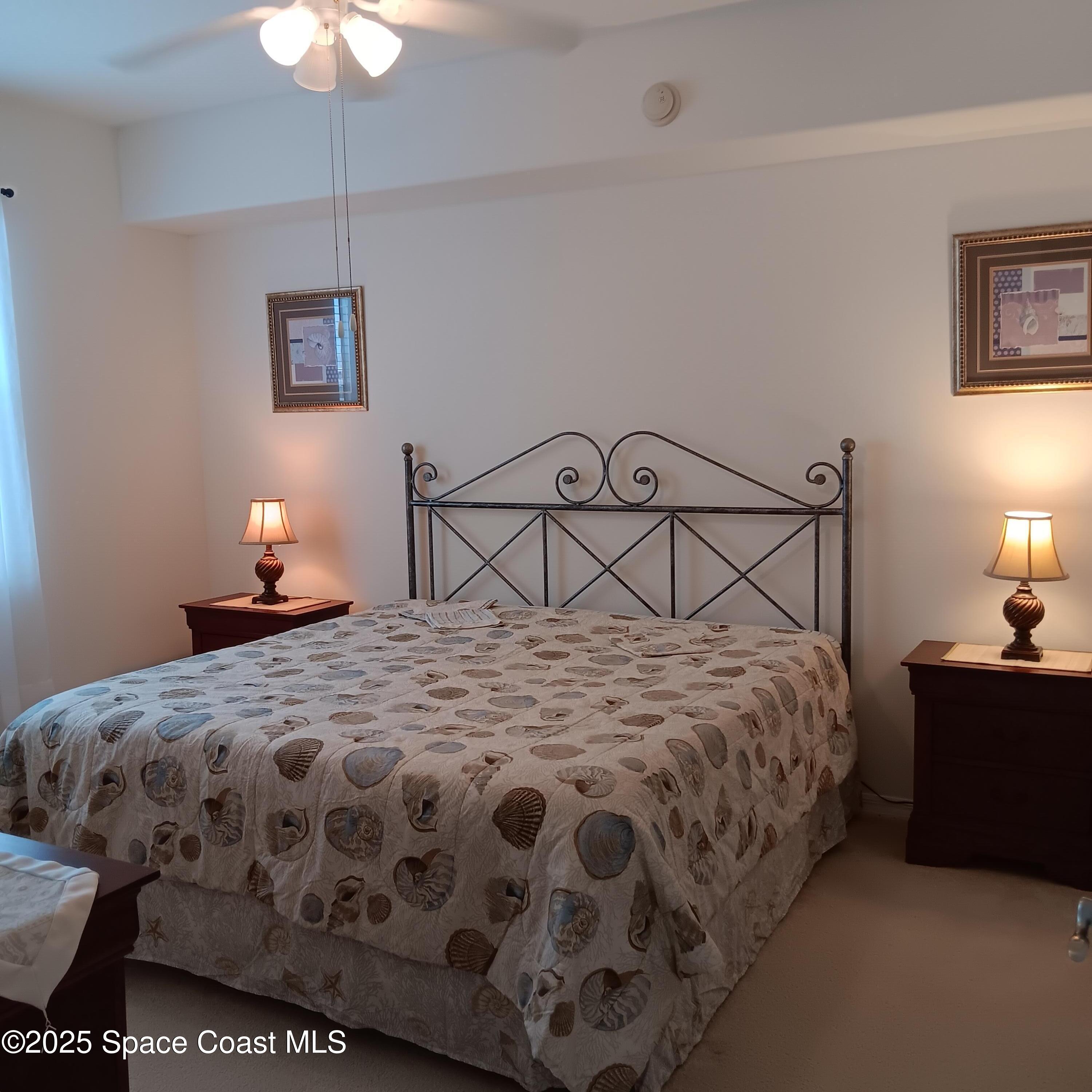 6858 Toland Drive, Unit 304 Melbourne, FL 32940 - Photo 11 of 31 a bedroom with a bed a lamp and a chandelier