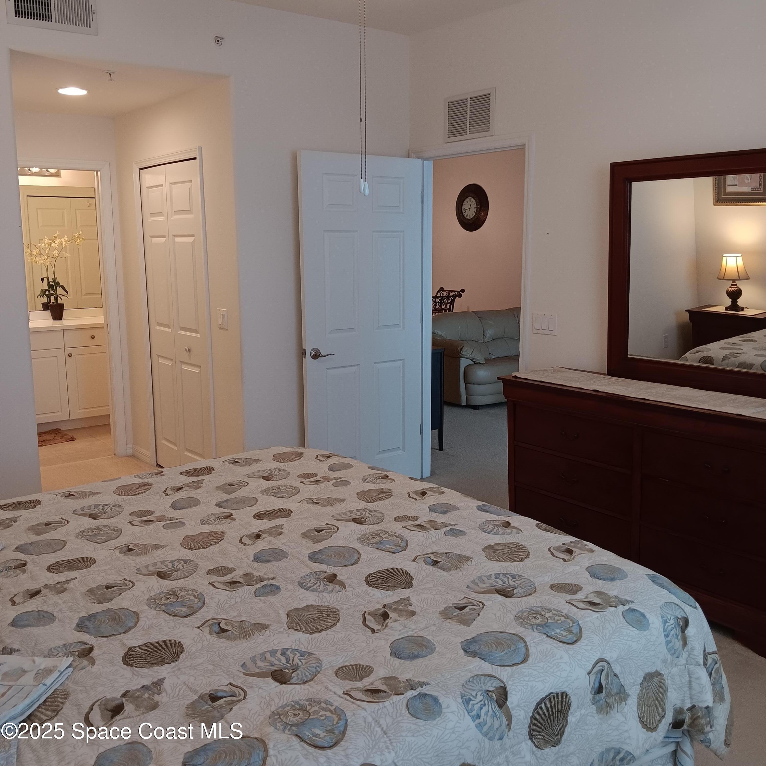 6858 Toland Drive, Unit 304 Melbourne, FL 32940 - Photo 13 of 31 a bedroom with a bed and a mirror