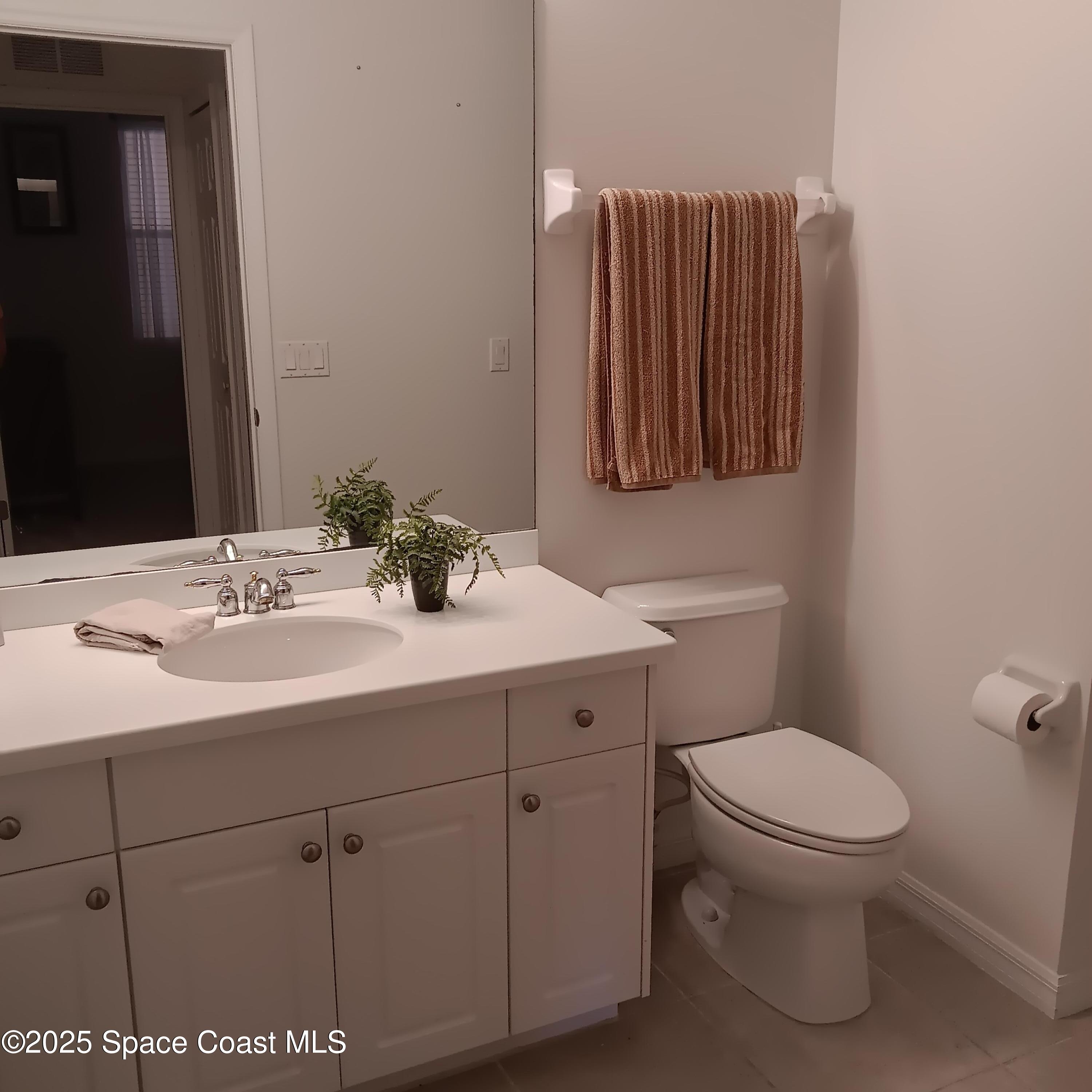 6858 Toland Drive, Unit 304 Melbourne, FL 32940 - Photo 21 of 31 a bathroom with a toilet sink and mirror
