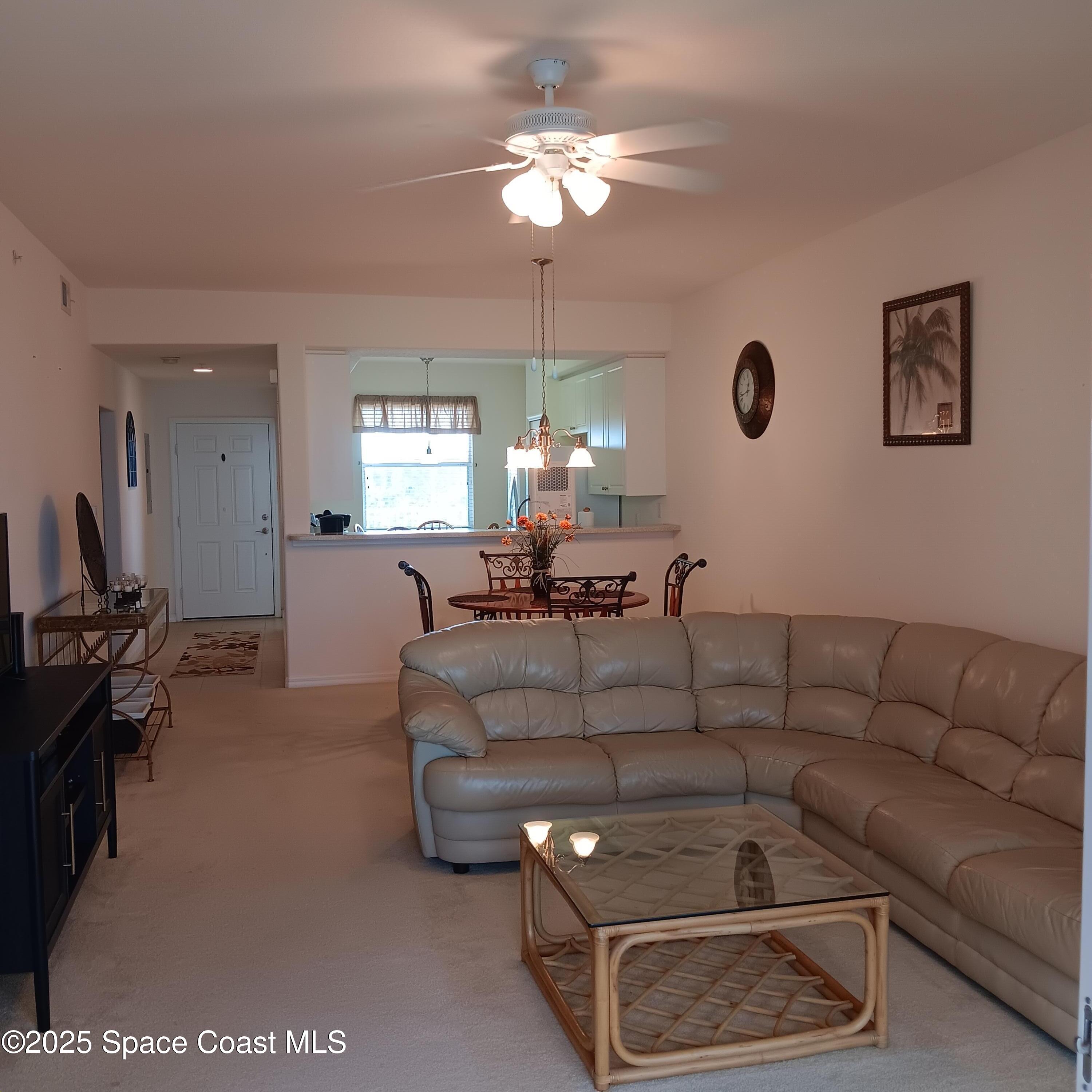 6858 Toland Drive, Unit 304 Melbourne, FL 32940 - Photo 9 of 31 a living room with furniture a chandelier a rug and a chandelier