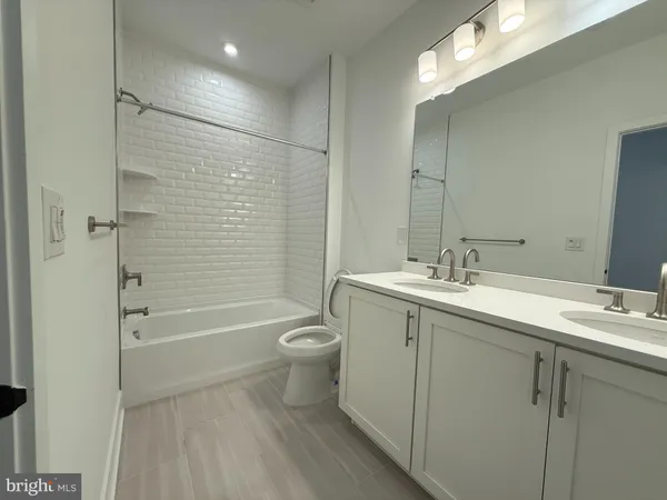 a bathroom with a bathtub shower sink vanity mirror and toilet