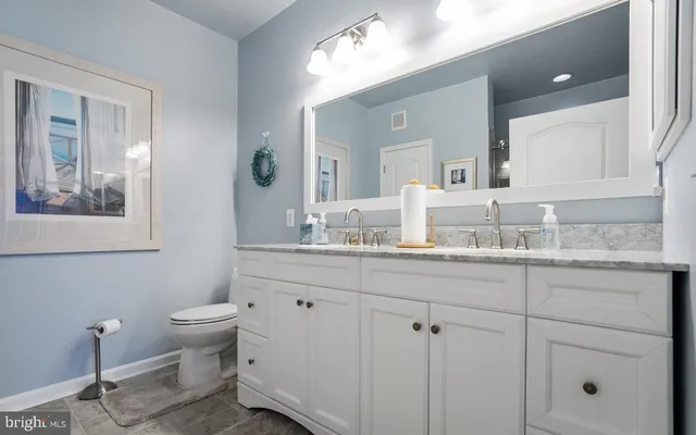 a bathroom with a granite countertop sink mirror and toilet