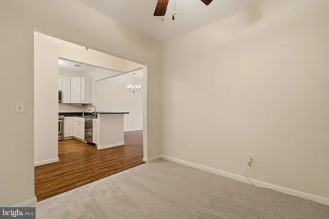 a view of an empty room with chandelier fan and wooden floor