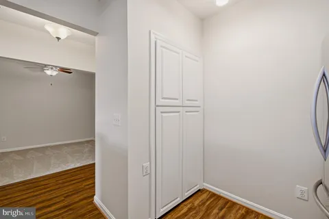 an empty room with wooden floor chandelier fan and windows