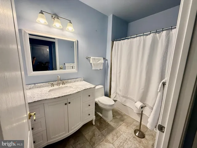a bathroom with a granite countertop sink toilet and mirror