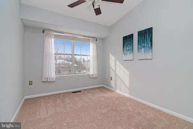 a view of an empty room with window and chandelier fan
