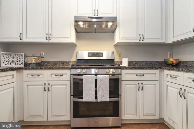 a kitchen with granite countertop white cabinets and a stove