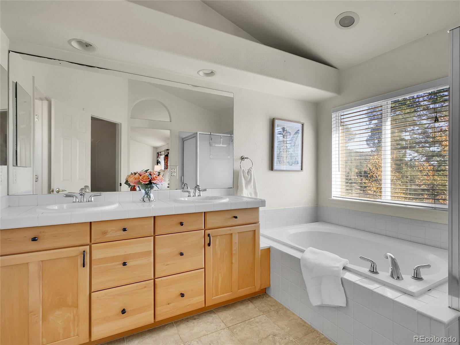 13586 Wamblee Trail Conifer, CO 80433 - Photo 15 of 38 a spacious bathroom with double vanity sinks a large mirror and a bathtub