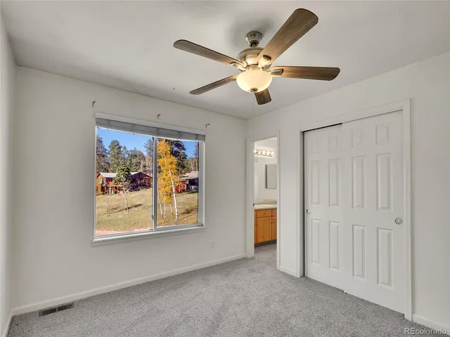 an empty room with window and ceiling fan