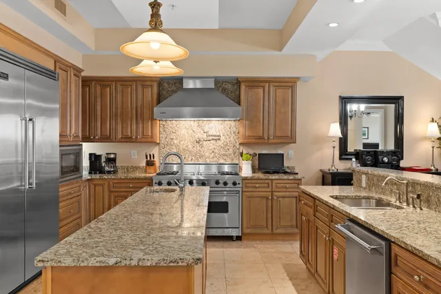 a kitchen with stainless steel appliances granite countertop sink stove refrigerator and cabinets