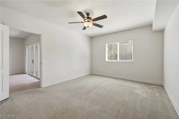 a view of an empty room with a ceiling fan and window