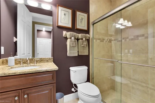 a bathroom with a toilet sink vanity granite and shower