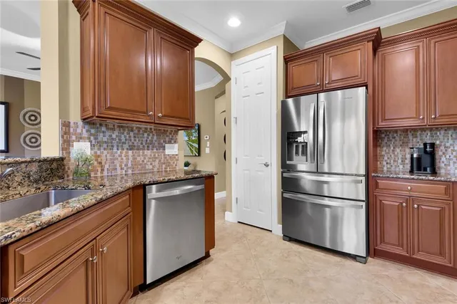 a kitchen with stainless steel appliances granite countertop a refrigerator a sink and white cabinets