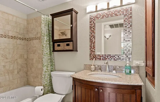 a bathroom with a granite countertop toilet a sink and a mirror
