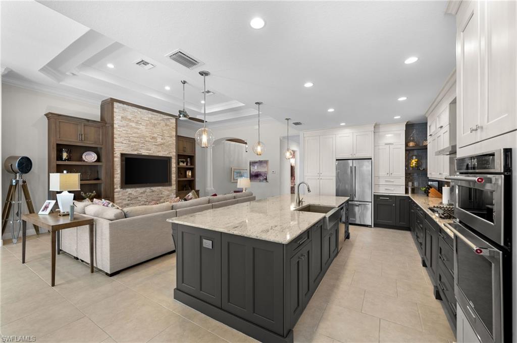 10067 Palazzo Drive Naples, FL 34119 - Photo 12 of 46 a large kitchen with stainless steel appliances kitchen island granite countertop a large counter top stainless steel appliances a chimney and a center island