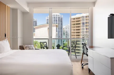 a bedroom with a bed and a table next to a window