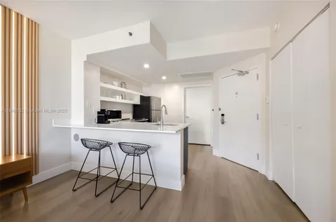 a kitchen with stainless steel appliances a refrigerator a stove a sink dishwasher and white cabinets with wooden floor