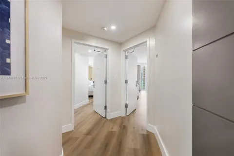 a view of a hallway with wooden floor and a bathroom