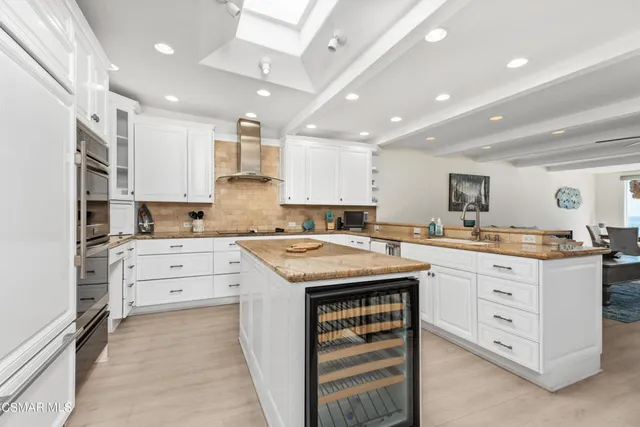 a kitchen with granite countertop a sink stove oven and white cabinets with wooden floor