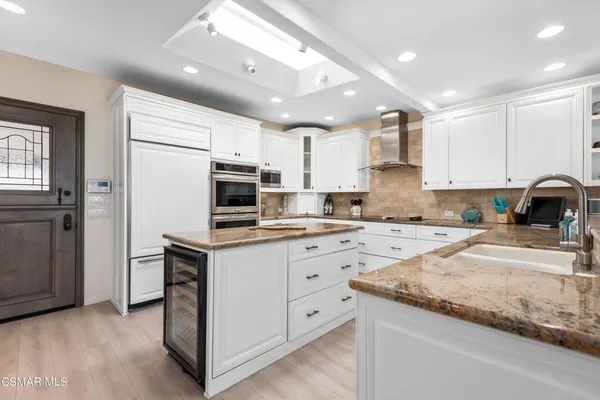 a kitchen with granite countertop a sink stainless steel appliances and white cabinets