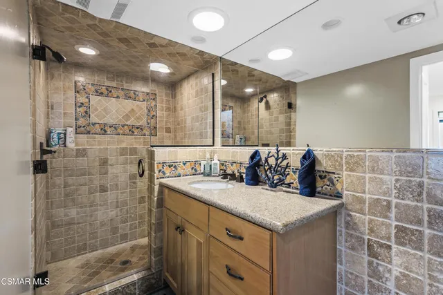 a bathroom with a granite countertop sink a large mirror and shower