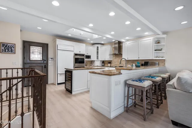 a kitchen with stainless steel appliances kitchen island granite countertop a stove top oven a sink a refrigerator and white cabinets