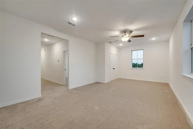 an empty room with a chandelier fan and windows