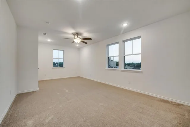 an empty room with windows and chandelier fan