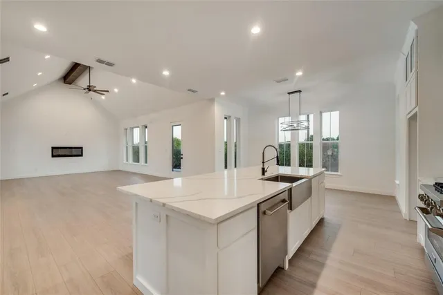 a large white kitchen with a sink and dishwasher