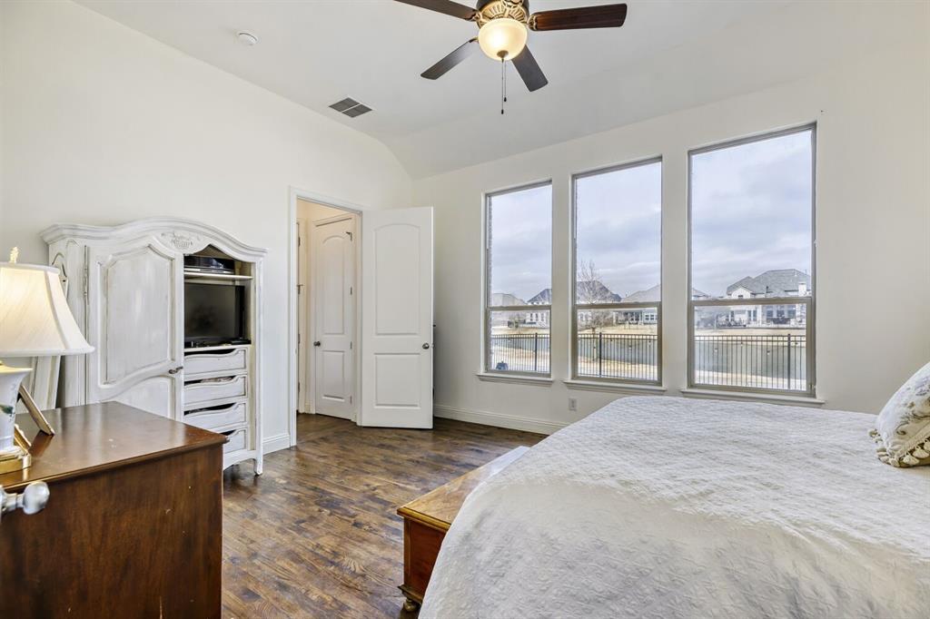 1425 Wildrye Ridge Celina, TX 75009 - Photo 18 of 32 a spacious bedroom with a large bed and a flat tv screen on dresser
