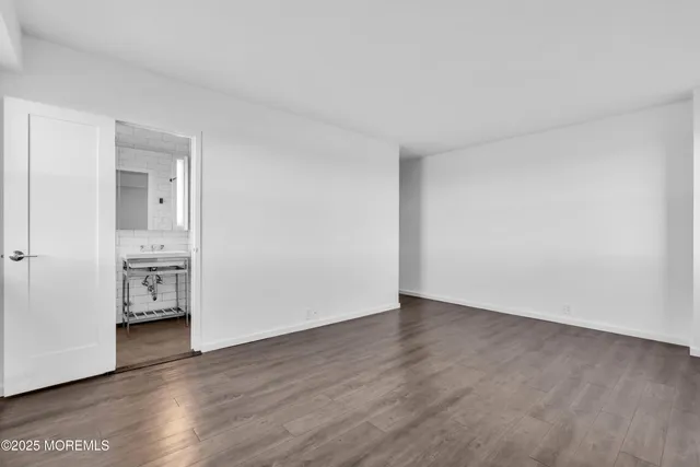 a view of an empty room with wooden floor and closet
