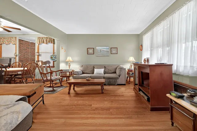 a living room with furniture a large window and wooden floor