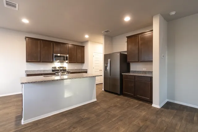 a kitchen with stainless steel appliances granite countertop a refrigerator a sink a stove a microwave and cabinets