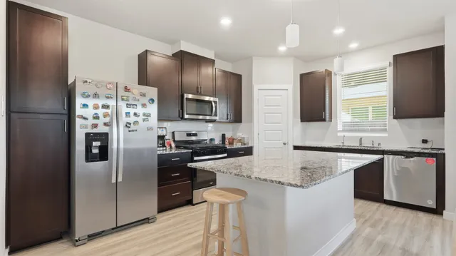 a kitchen with stainless steel appliances granite countertop a refrigerator stove microwave and sink