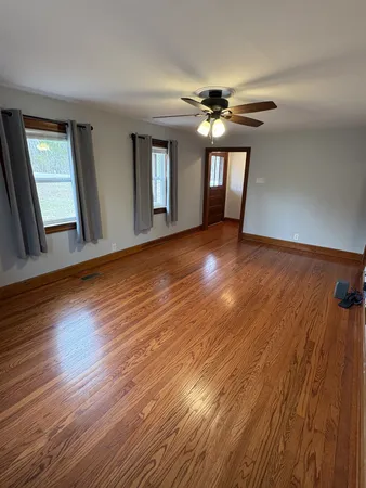 a view of an empty room with window and wooden floor