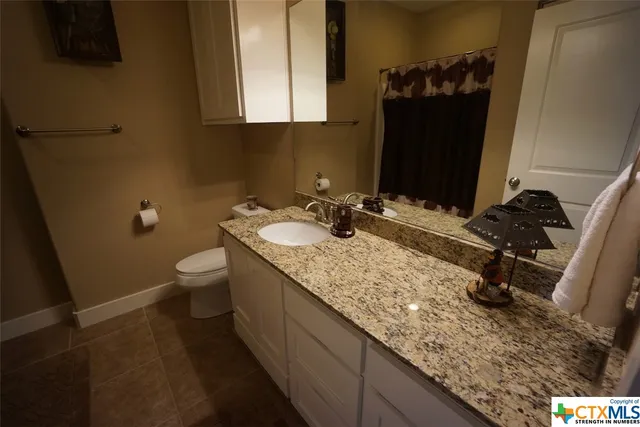 a bathroom with a granite countertop sink a toilet and a mirror