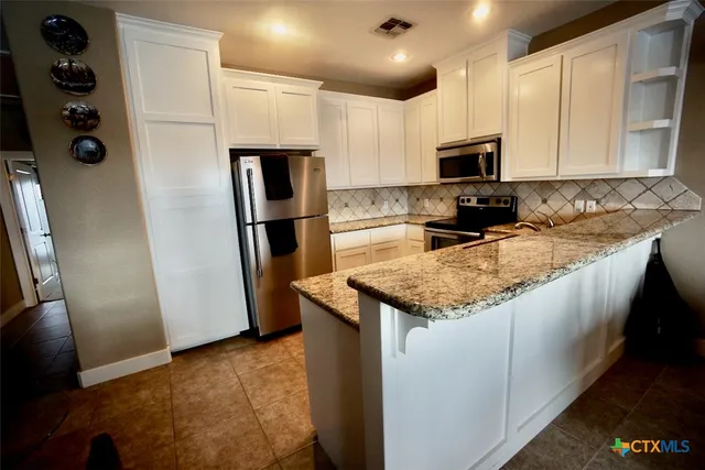 a living room with stainless steel appliances kitchen island granite countertop a sink and cabinets