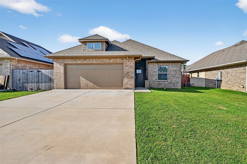 View of front of house featuring brick siding, an attached garage, concrete driveway, and roof with shingles