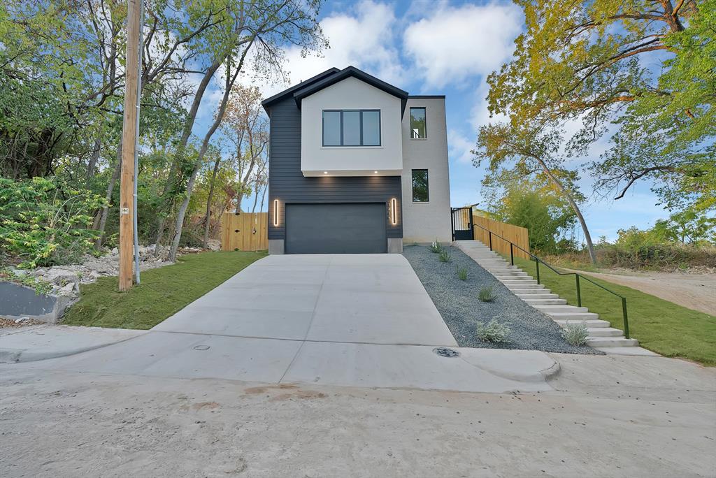 1415 Fayette Street Dallas, TX 75203 - Photo 1 of 40 Contemporary exterior with dark siding and light stucco accents, a two-car garage, and a concrete driveway