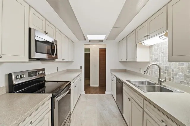 a kitchen with stainless steel appliances granite countertop a sink stove microwave and refrigerator