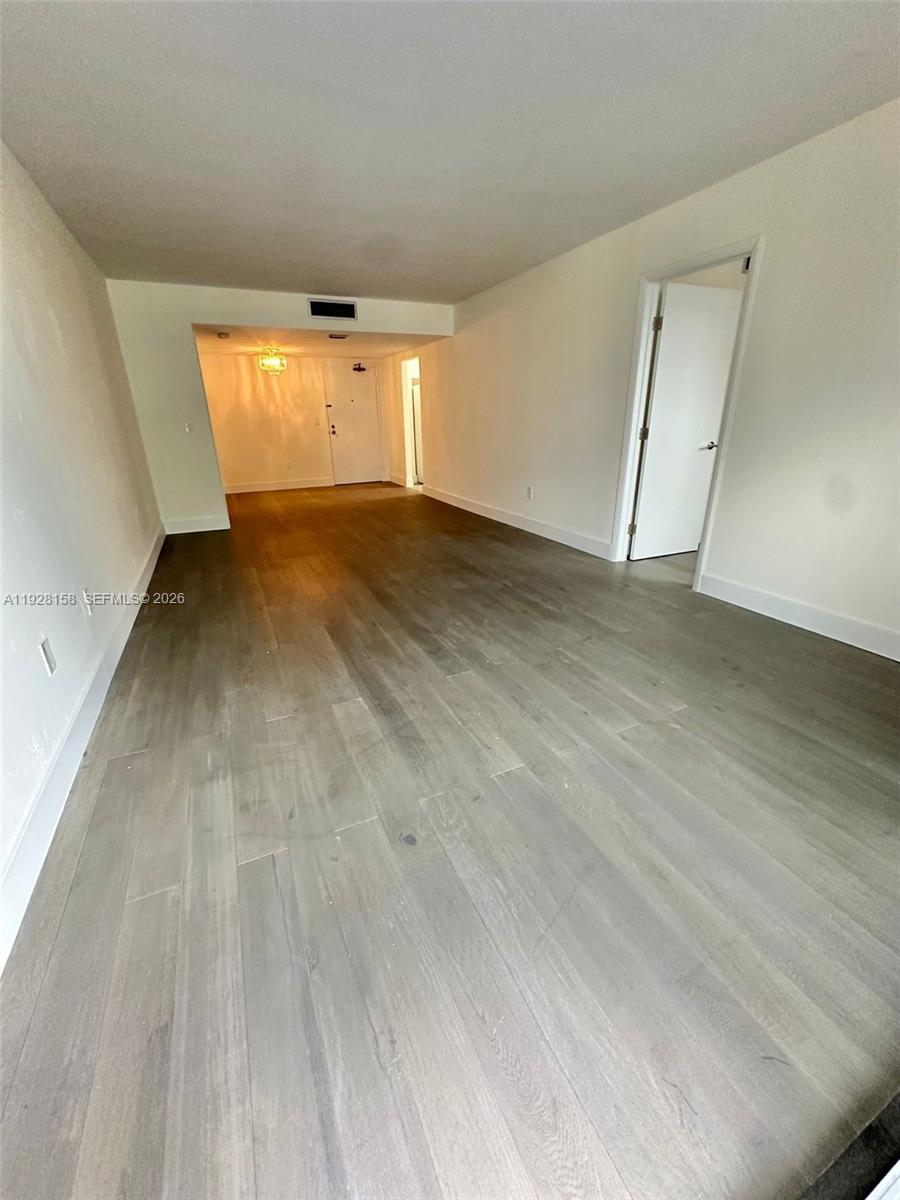 9273 Collins Avenue, Unit 207 Surfside, FL 33154 - Photo 3 of 14 an empty room with wooden floor and windows