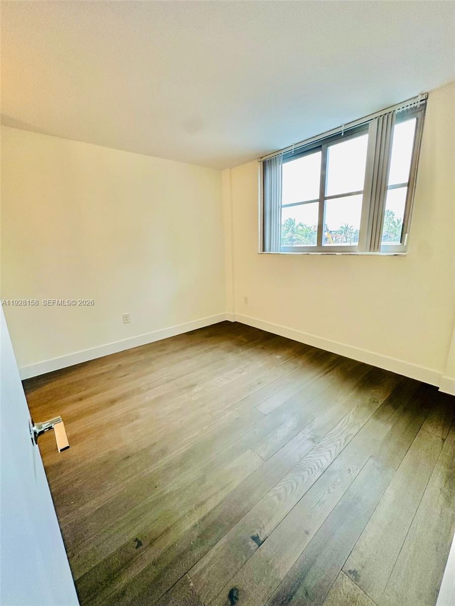 9273 Collins Avenue, Unit 207 Surfside, FL 33154 - Photo 6 of 14 an empty room with wooden floor and windows