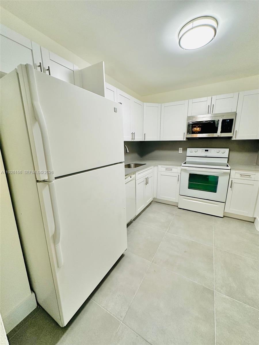 9273 Collins Avenue, Unit 207 Surfside, FL 33154 - Photo 8 of 14 a white refrigerator freezer sitting in a kitchen